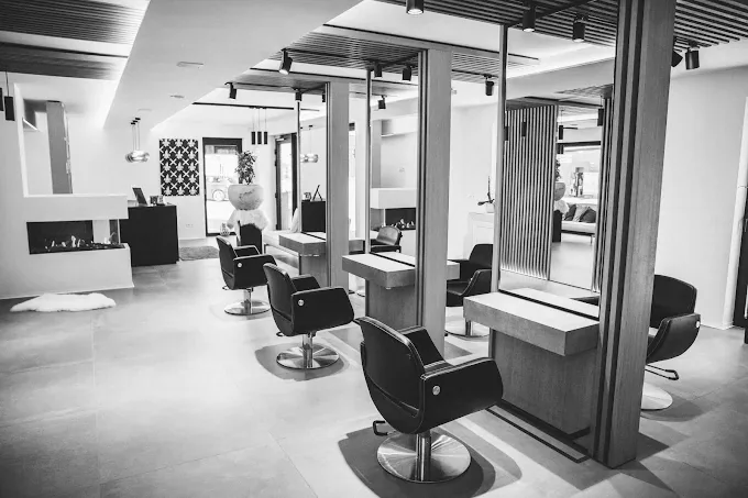 Behandelplaatsen van kapsalon Elle Coiffure in Borgloon met spiegels, kaptafels en haard